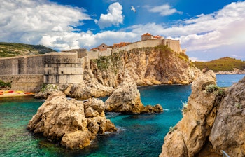 Dubrovniks historiske bymure og fæstning beliggende på klipper ved Adriaterhavets turkisblå vand i Kroatien