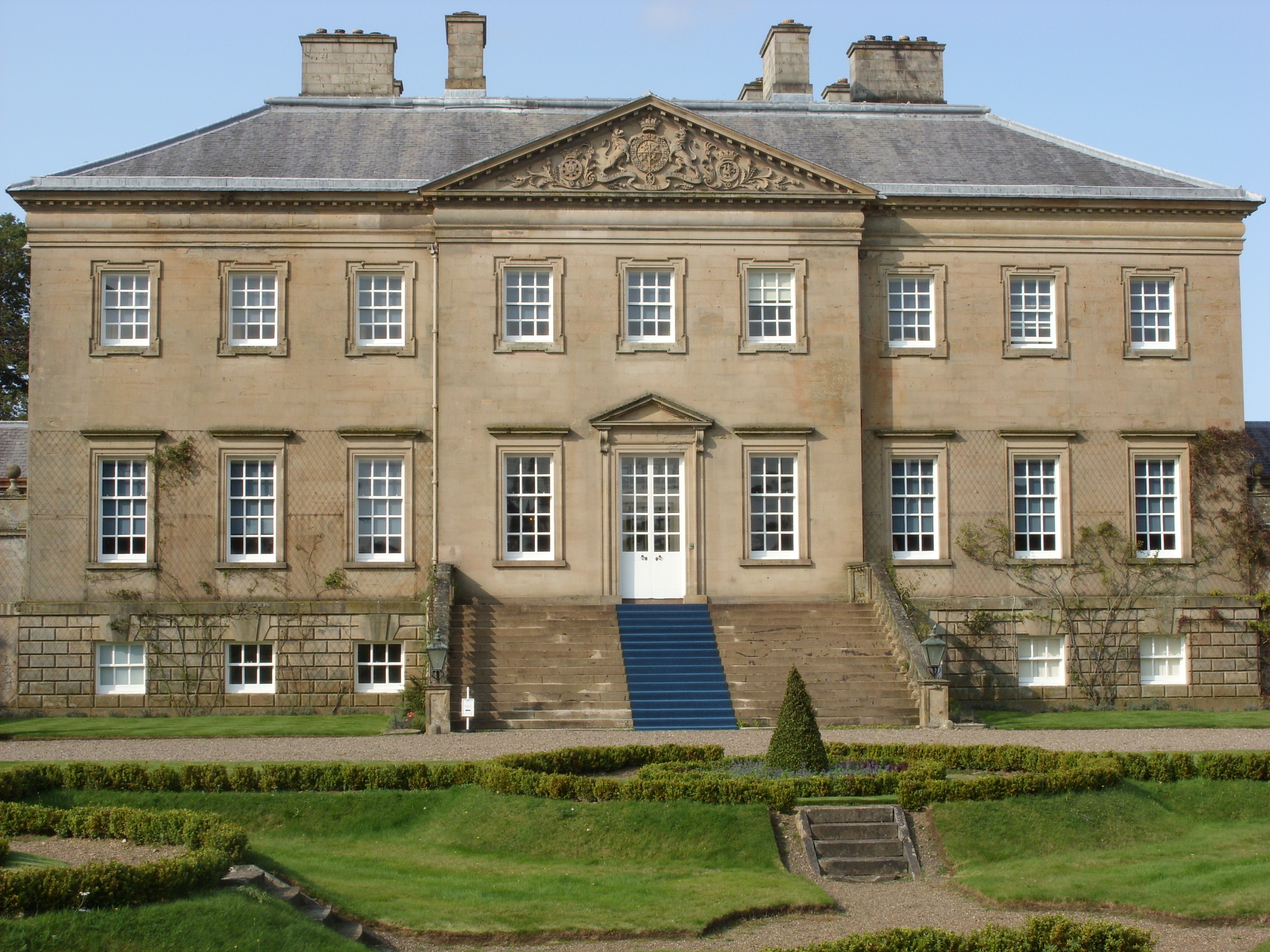 Den smukke georgiske facade på Dumfries House i Ayrshire, Skotland, med velpleje formelle haver foran bygningen