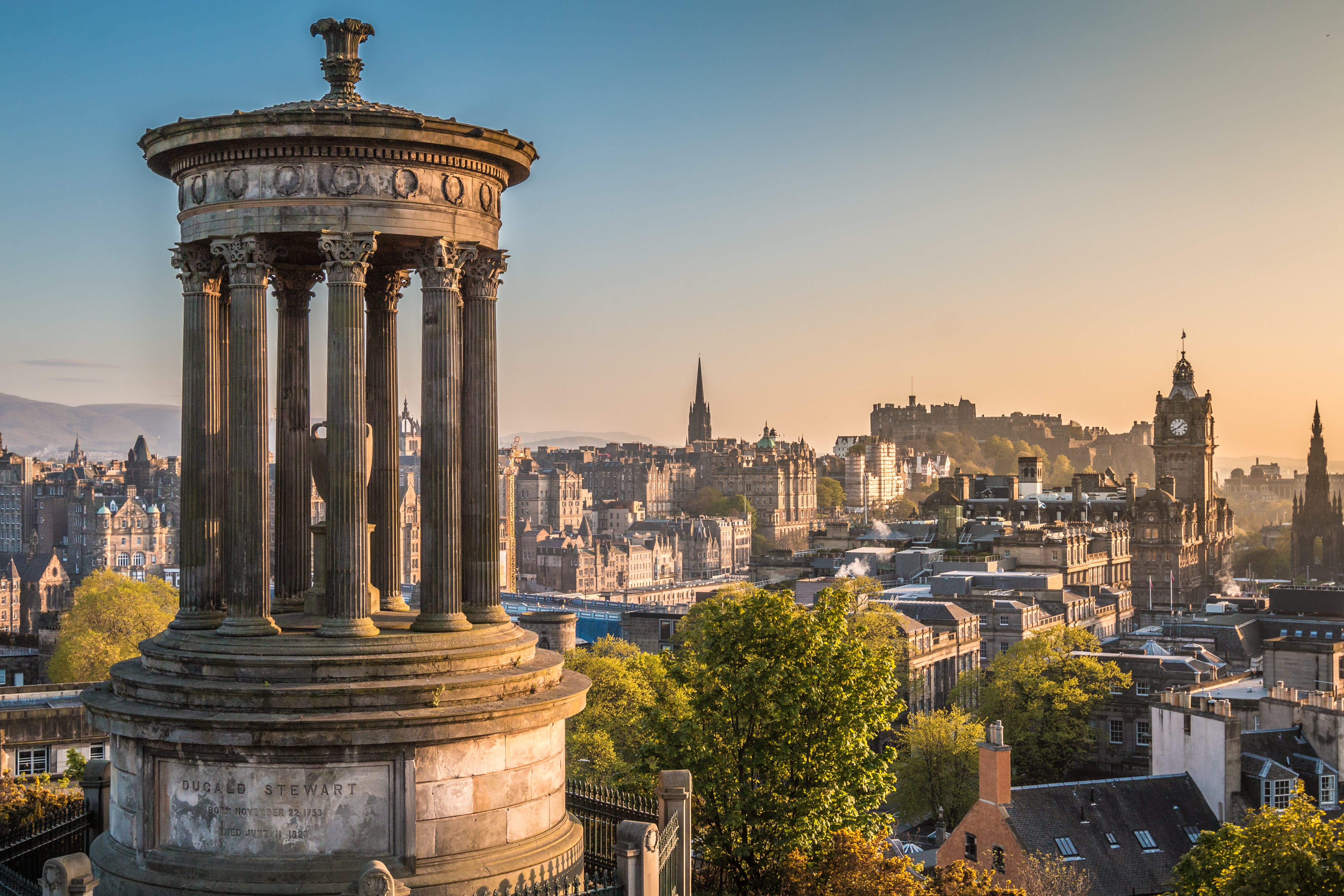 Smuk panoramaudsigt over Edinburgh fra Calton Hill med historisk monument og byens skyline i solnedgangslys