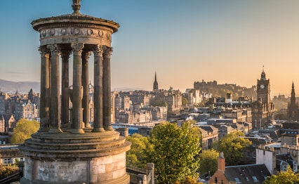 Smuk panoramaudsigt over Edinburgh fra Calton Hill med historisk monument og byens skyline i solnedgangslys