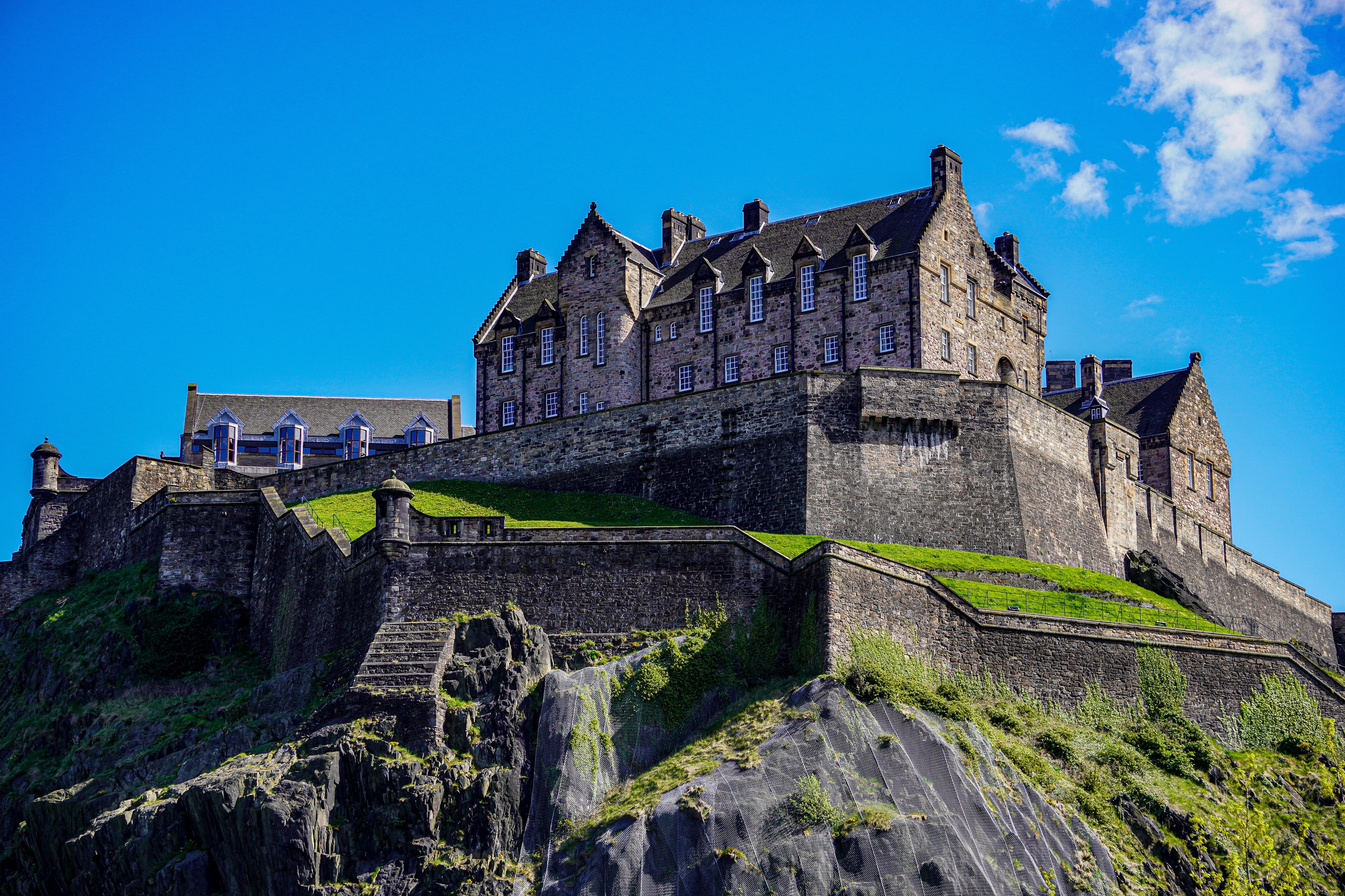 Edinburgh Castle tronende på vulkansk klippe under strålende blå himmel med historiske middelalderlige fæstningsmure i Skotland