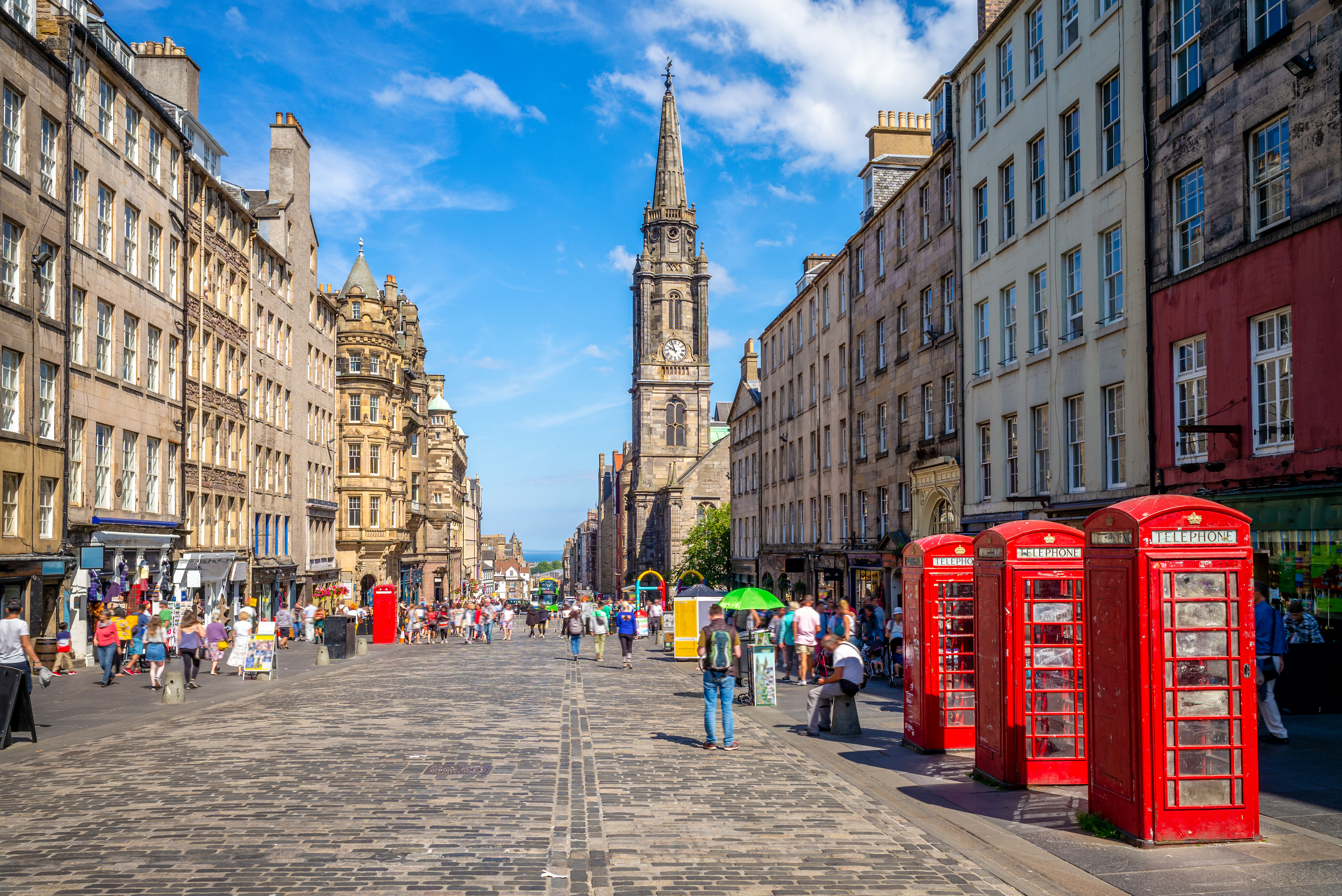 Edinburgh Royal Mile med historiske bygninger, kirketårn og røde telefonbokse på solskinsdag