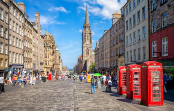 Edinburgh Royal Mile med historiske bygninger, kirketårn og røde telefonbokse på solskinsdag
