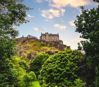 Edinburgh slot badet i aftenlys set fra Princes Park, historisk skotsk fæstning på Castle Rock
