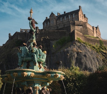 Edinburgh Castle troner majestætisk over byen med Ross fontænen i forgrunden - et ikonisk symbol på Skotlands rige historie