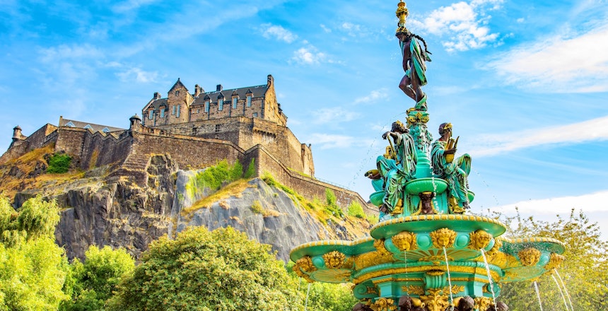 Historiske Edinburgh Slot og det farverige Ross Springvand under blå himmel i Skotlands hovedstad, perfekt udflugtsmål på rejsen