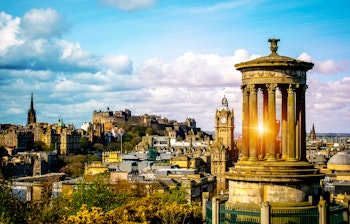 Historisk udsigt over Edinburgh ved solnedgang med Dugald Stewart monumentet på Calton Hill og Edinburgh Slot i baggrunden