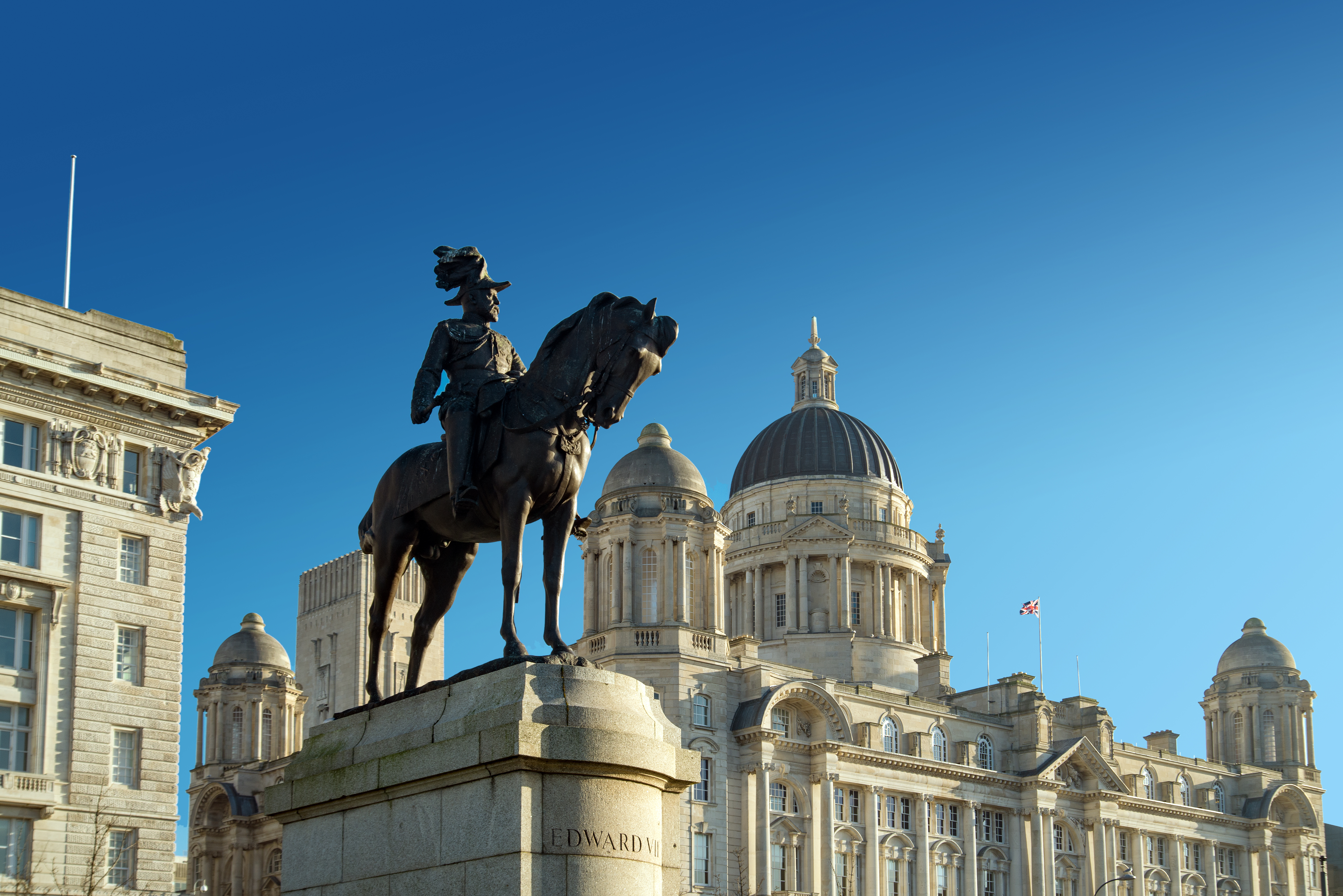 Historisk statue af Kong Edward VII foran den imponerende Port of Liverpool bygning med karakteristisk kuppel, en del af de berømte Tre Gracer ved Liverpools havnefront