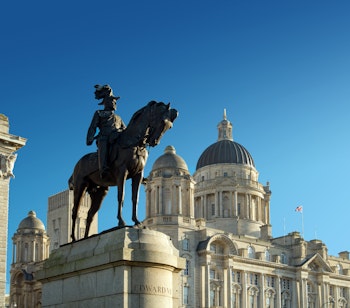 Historisk statue af Kong Edward VII foran den imponerende Port of Liverpool bygning med karakteristisk kuppel, en del af de berømte Tre Gracer ved Liverpools havnefront