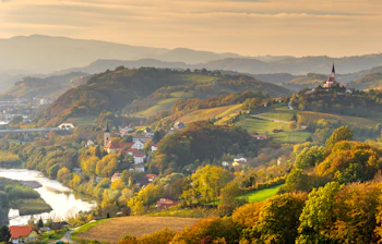 Betagende efterårsudsigt over vinmarkerne i Ptuj-regionen i Slovenien med en malerisk landsby og kirketårn på bakketoppen