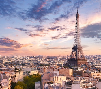 Betagende udsigt over Eiffeltårnet i Paris ved solnedgang med byens panorama og en farverig aftenhimmel