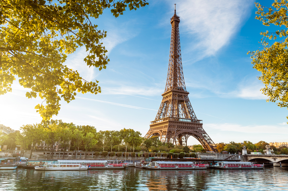 Eiffeltårnet set fra Seine-floden med turistbåde under solnedgang i Paris Frankrig