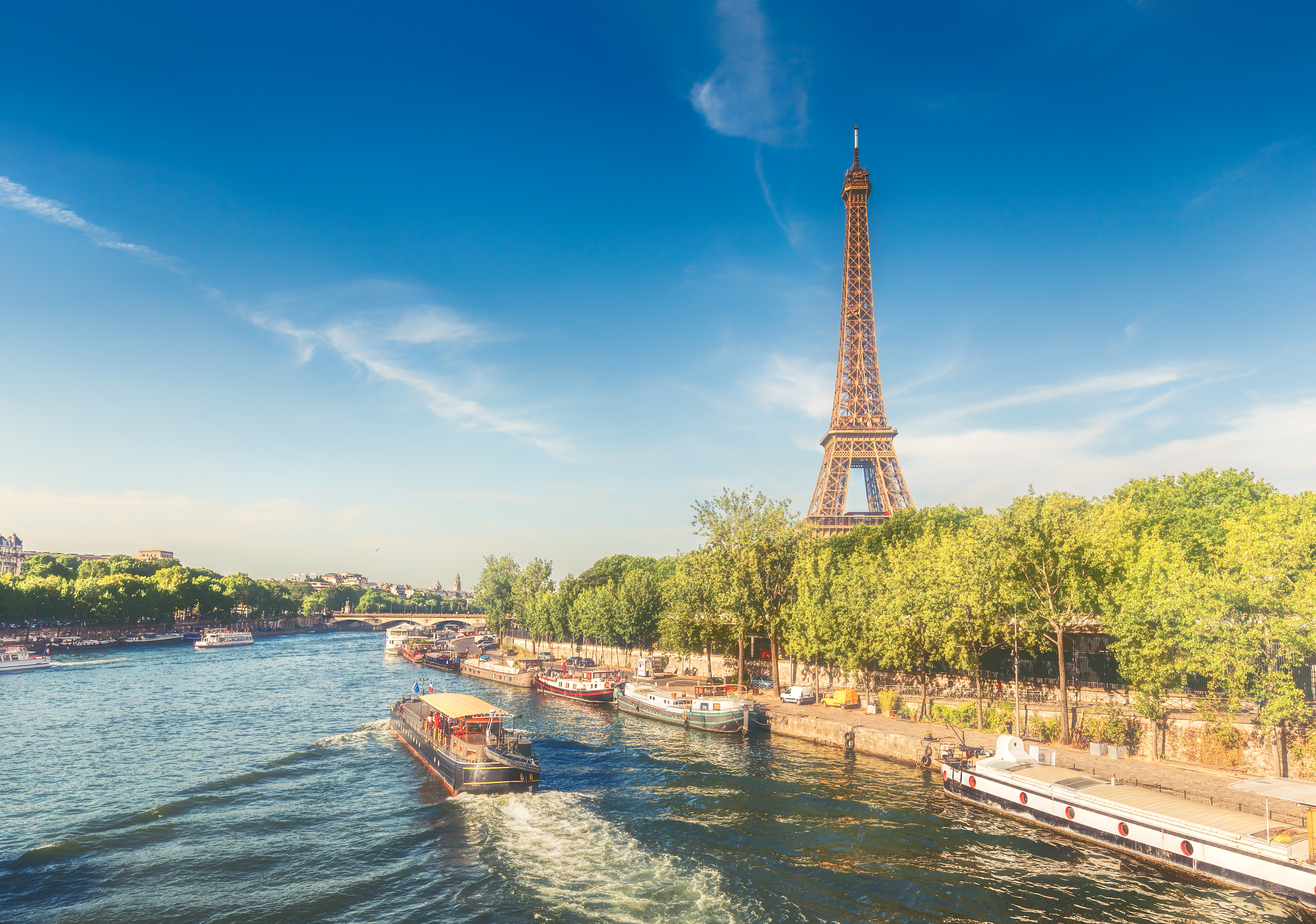 Eiffeltårnet og krydstogtbåde på Seine-floden i Paris på en solrig sommerdag