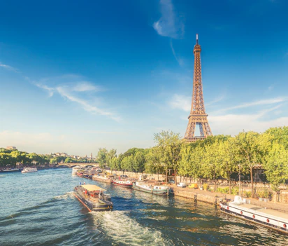 Eiffeltårnet og krydstogtbåde på Seine-floden i Paris på en solrig sommerdag