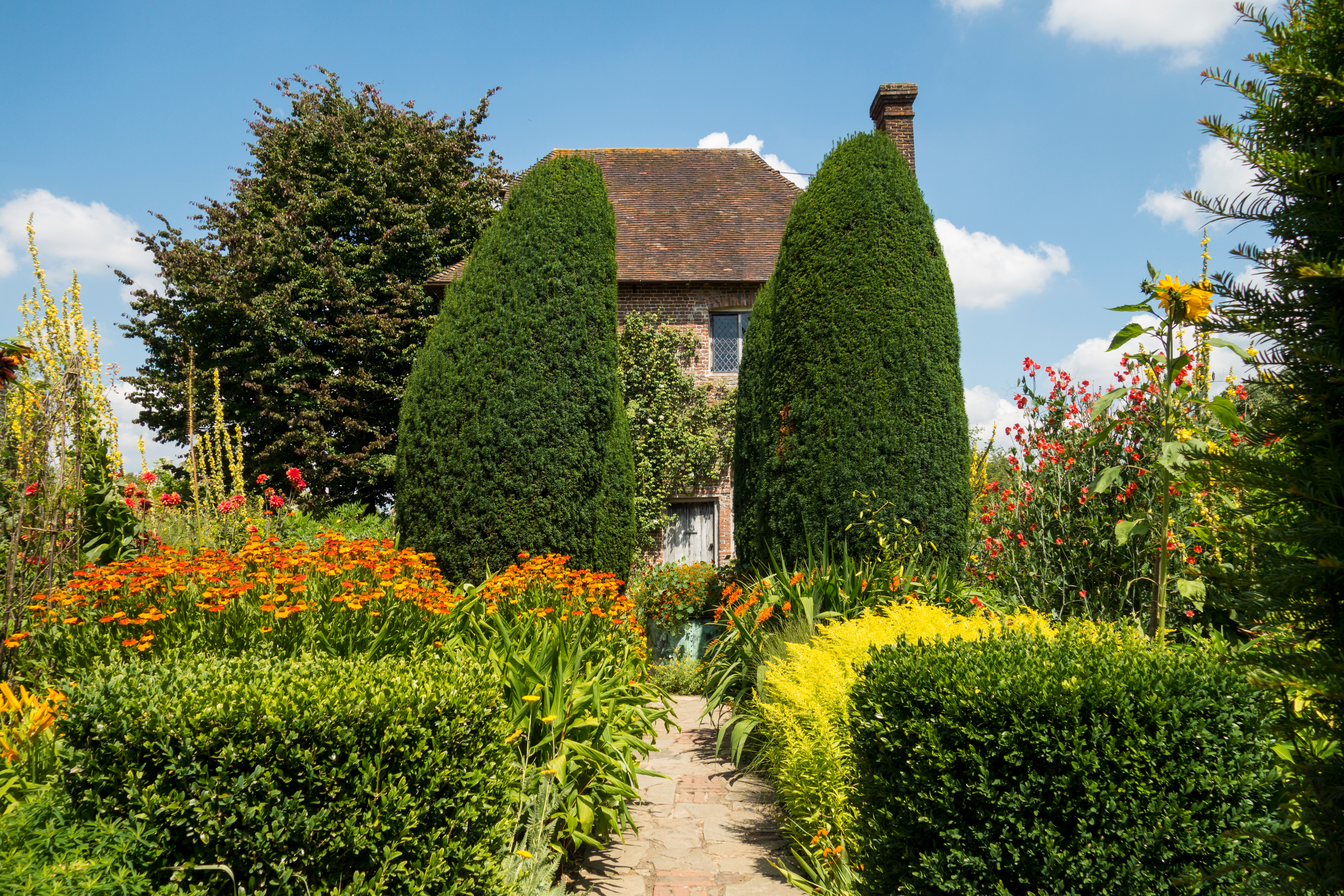 Smuk engelsk cottage have med farverige sommerblomster og traditionel arkitektur