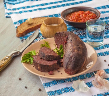 Traditionel estisk verivorst blodpølse serveret med brød og tilbehør på en blåstribet dug, en delikatesse fra det estiske køkken