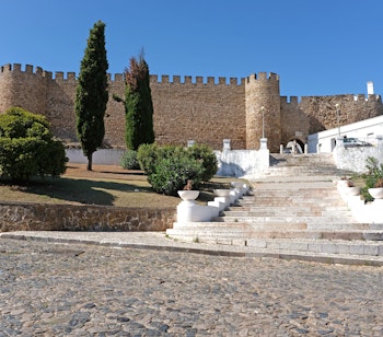 Historisk fæstningsmur i Estremoz med marmortrappe, cyprestræer og den karakteristiske hvide arkitektur i Alentejo-regionen i Portugal