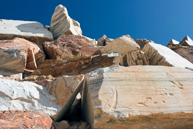 Imponerende blokke af rå hvid og rosa marmor i det berømte stenbrud i Estremoz, Alentejo, hvor Portugals fineste marmor udvindes under den klare blå himmel