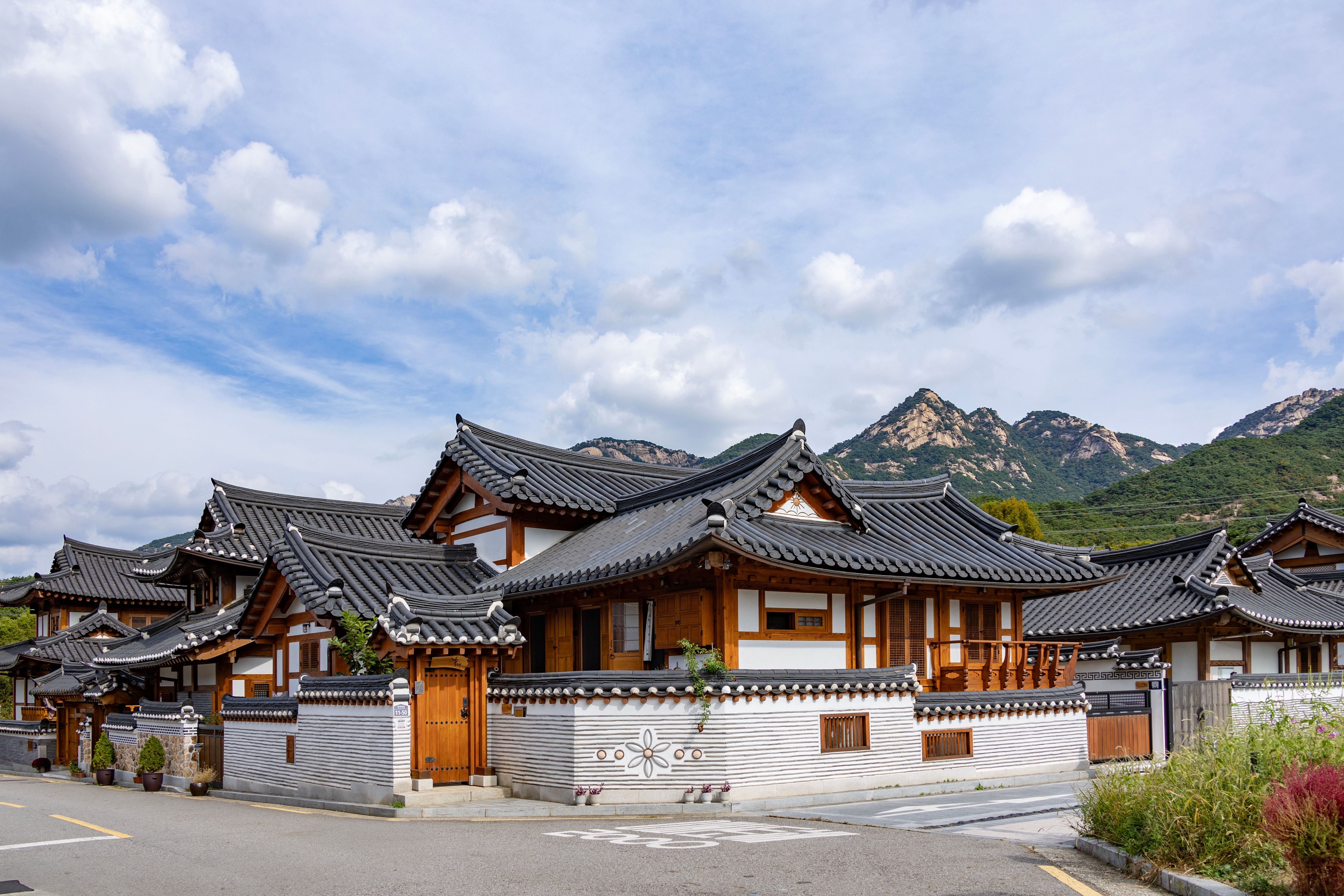 Idyllisk udsigt over Eunpyeong Hanok-landsbyen i Seoul med traditionelle koreanske huse med buede tage, stenbelagte stier og smukke bjerge i baggrunden