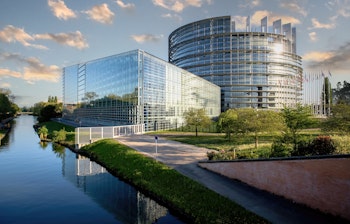 Europa-Parlamentets bygning i Strasbourg med EU-flag spejlet i Ill-floden - et symbolsk vartegn for europæisk samarbejde
