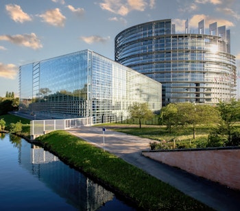 Europa-Parlamentets bygning i Strasbourg med EU-flag spejlet i Ill-floden - et symbolsk vartegn for europæisk samarbejde