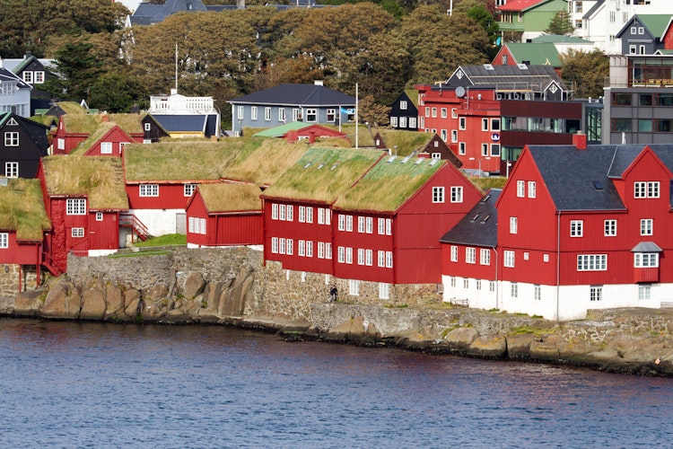 Traditionelle røde og hvide bygninger med græstage på Færøerne.