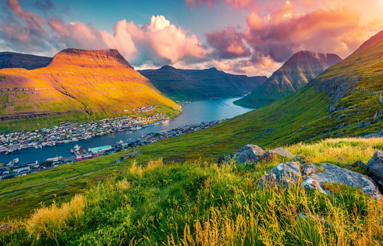 Spektakulær solnedgang over Klaksvik by set fra Klakkur-toppen på Færøerne, med fjorde og bjerge badet i gyldent aftenlys over Atlanterhavet