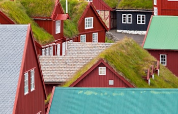 Idyllisk kystlandsby på Færøerne med farverige huse omgivet af dramatiske klipper og fjorde i vintage stil
