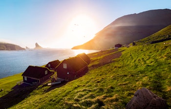 Idylliske færøske huse med grønne græstage ved solnedgang på Færøerne - en perfekt illustration af øernes unikke arkitektur og betagende natur