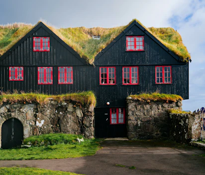 Traditionelle færøske græstagshuse med røde vinduer og stenmure
