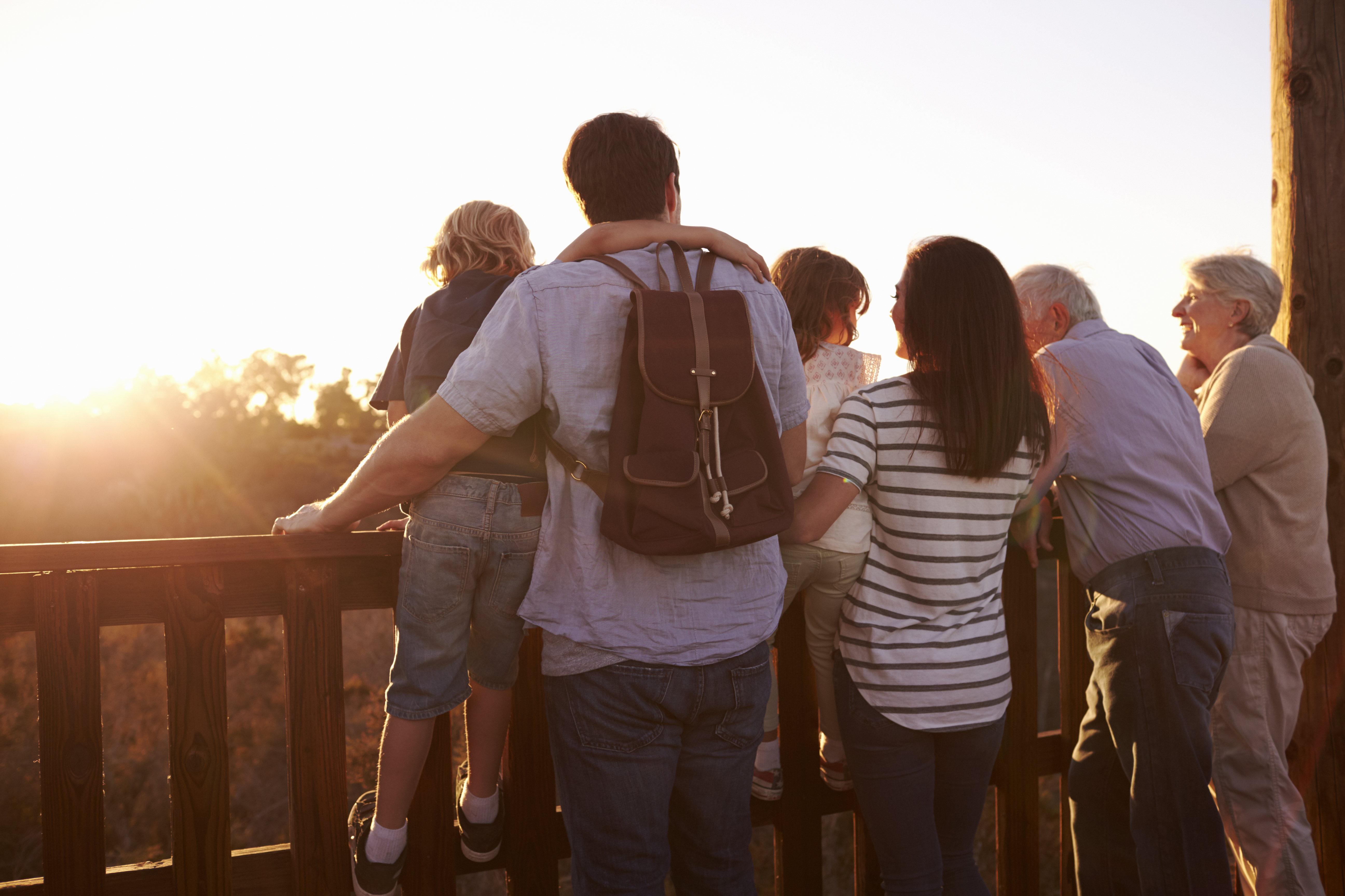 Tre generationer familie nyder solnedgang fra udsigtsplatform under ferie
