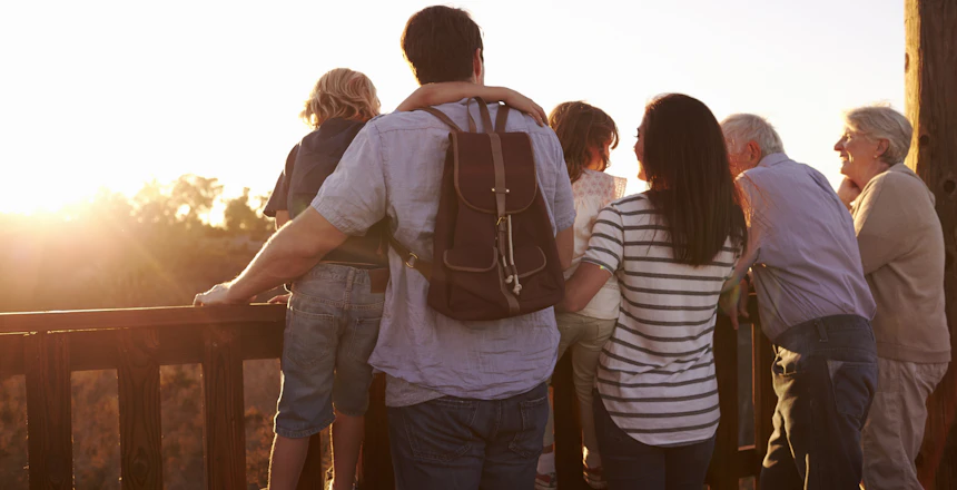 Tre generationer familie nyder solnedgang fra udsigtsplatform under ferie