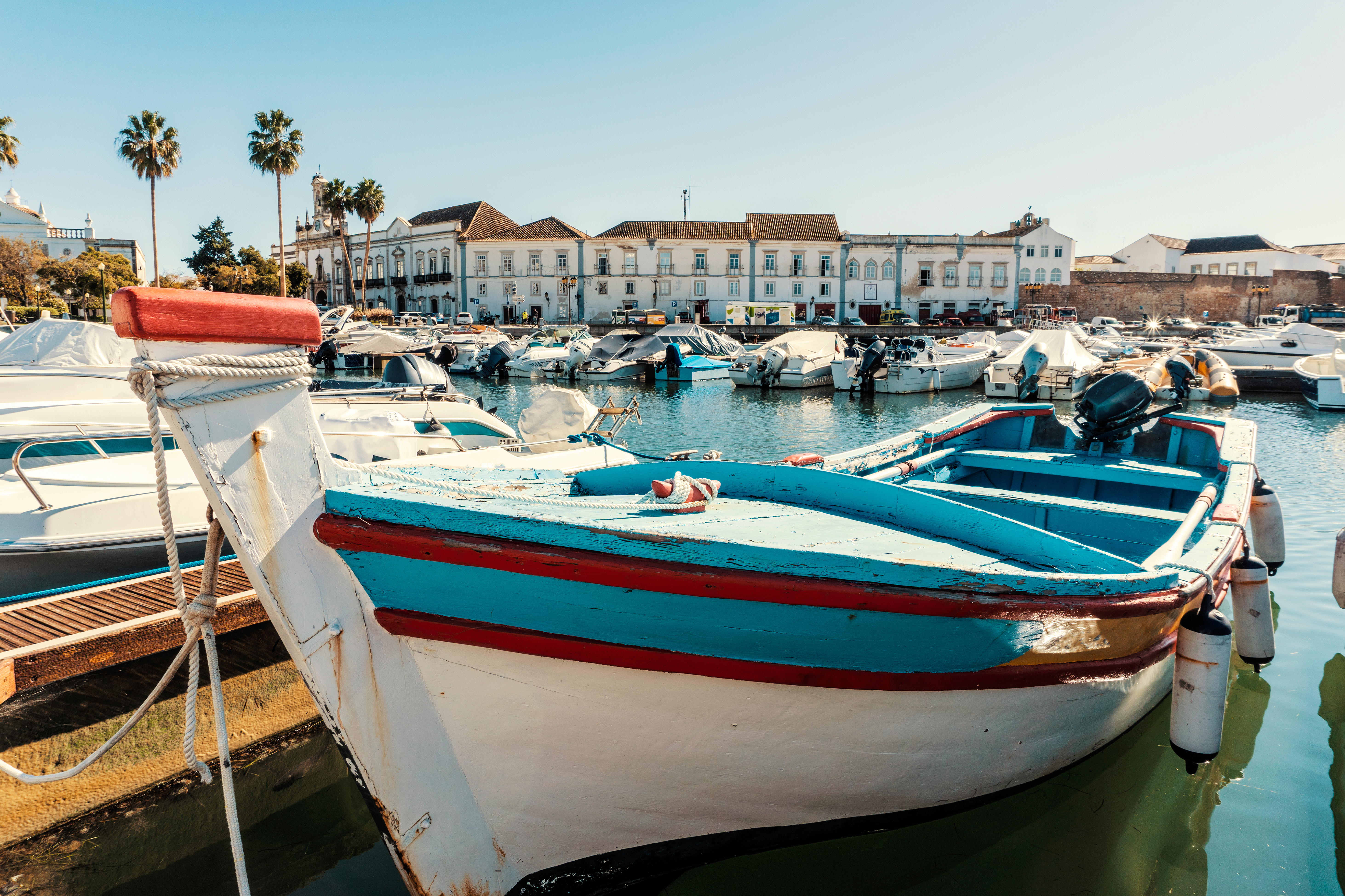 Traditionelle portugisiske fiskerbåde i Faro marina med historiske bygninger i Algarve