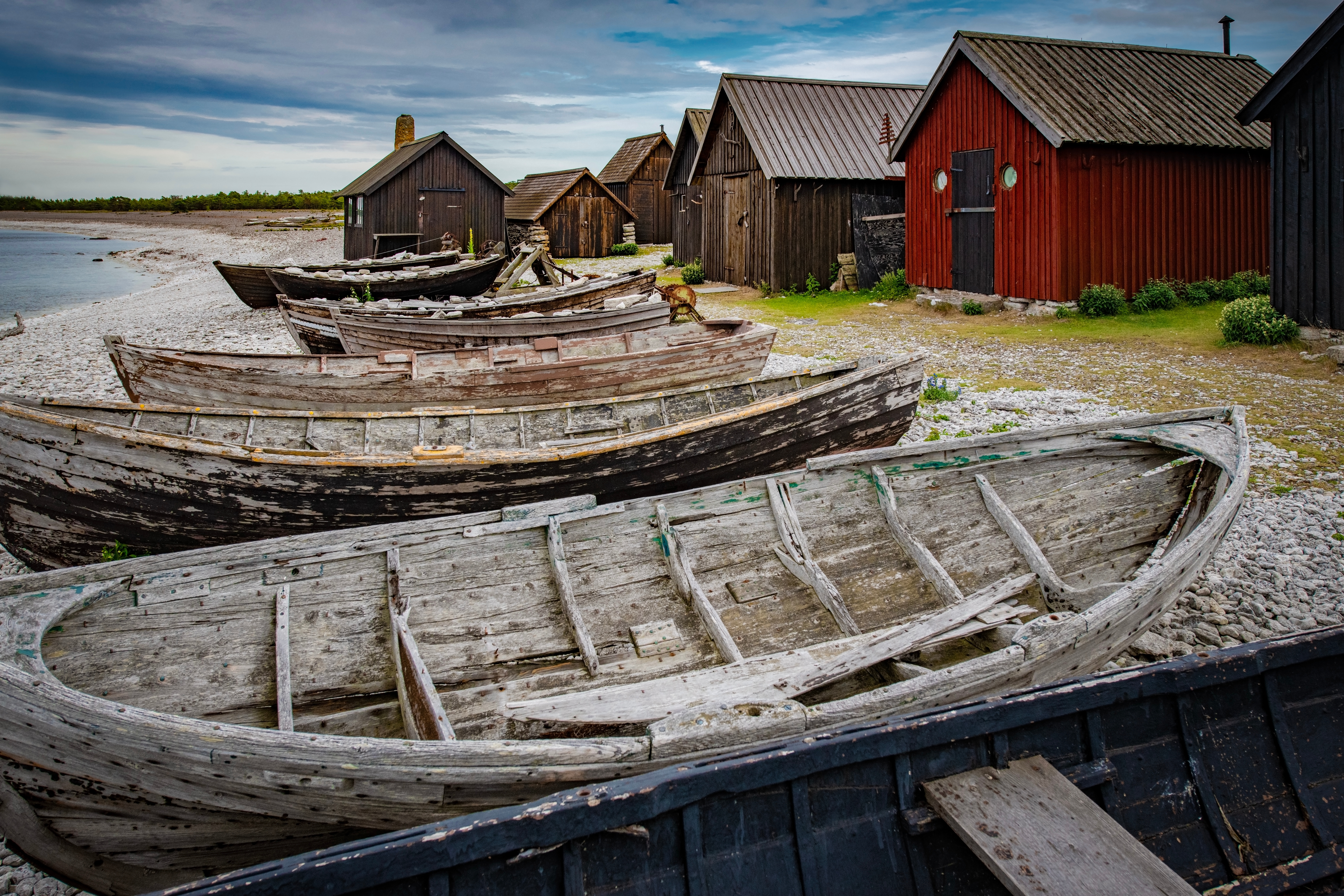 Traditionelle træfiskerbåde og røde hytter på Fårö strand, Gotland Sverige