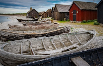 Traditionelle træfiskerbåde og røde hytter på Fårö strand, Gotland Sverige
