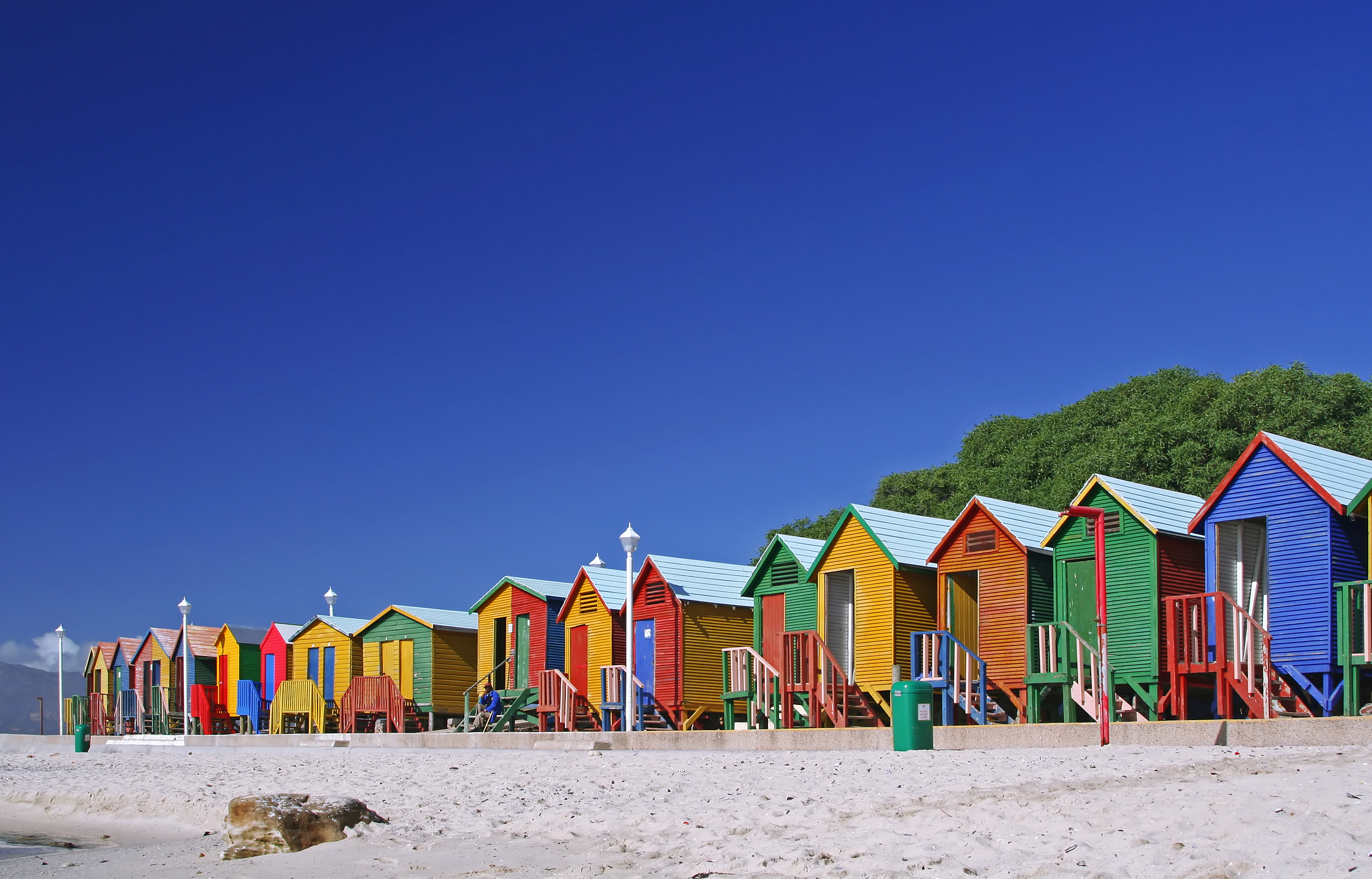 Farvestrålende strandhuse på St James Beach i Kapstad, Sydafrika under blå himmel