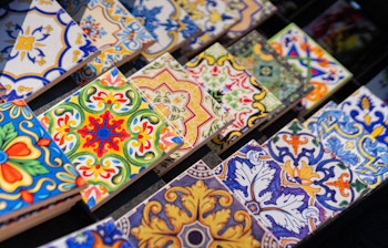Farverige portugisiske azulejo-fliser med traditionelle mønstre og designs udstillet som souvenirs på et marked i Lissabon, perfekt minde fra en rejse til Portugal