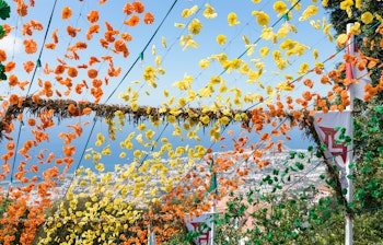 Farvestrålende gade pyntet med orange, gule og grønne blomsterguirlander der hænger på tværs af vejen under en traditionel kulturfestival