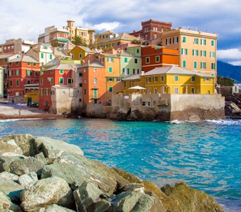 Malerisk udsigt over Boccadasse-distriktet i Genova med farverige bygninger langs den klippefyldte middelhavskyst