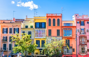 Farverige historiske bygningsfacader i Palma de Mallorca, der viser den charmerende middelhavsstil med levende farver under blå himmel