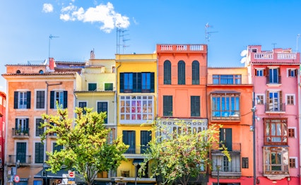 Farverige historiske bygningsfacader i Palma de Mallorca, der viser den charmerende middelhavsstil med levende farver under blå himmel