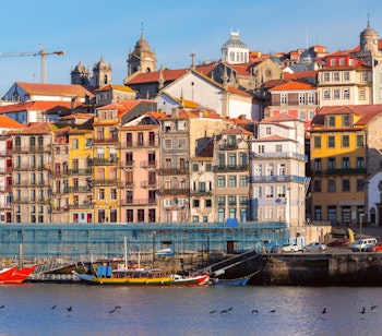Farverige historiske bygningsfacader i Ribeira-kvarteret i Porto, Portugal, med udsigt over floden i solskin