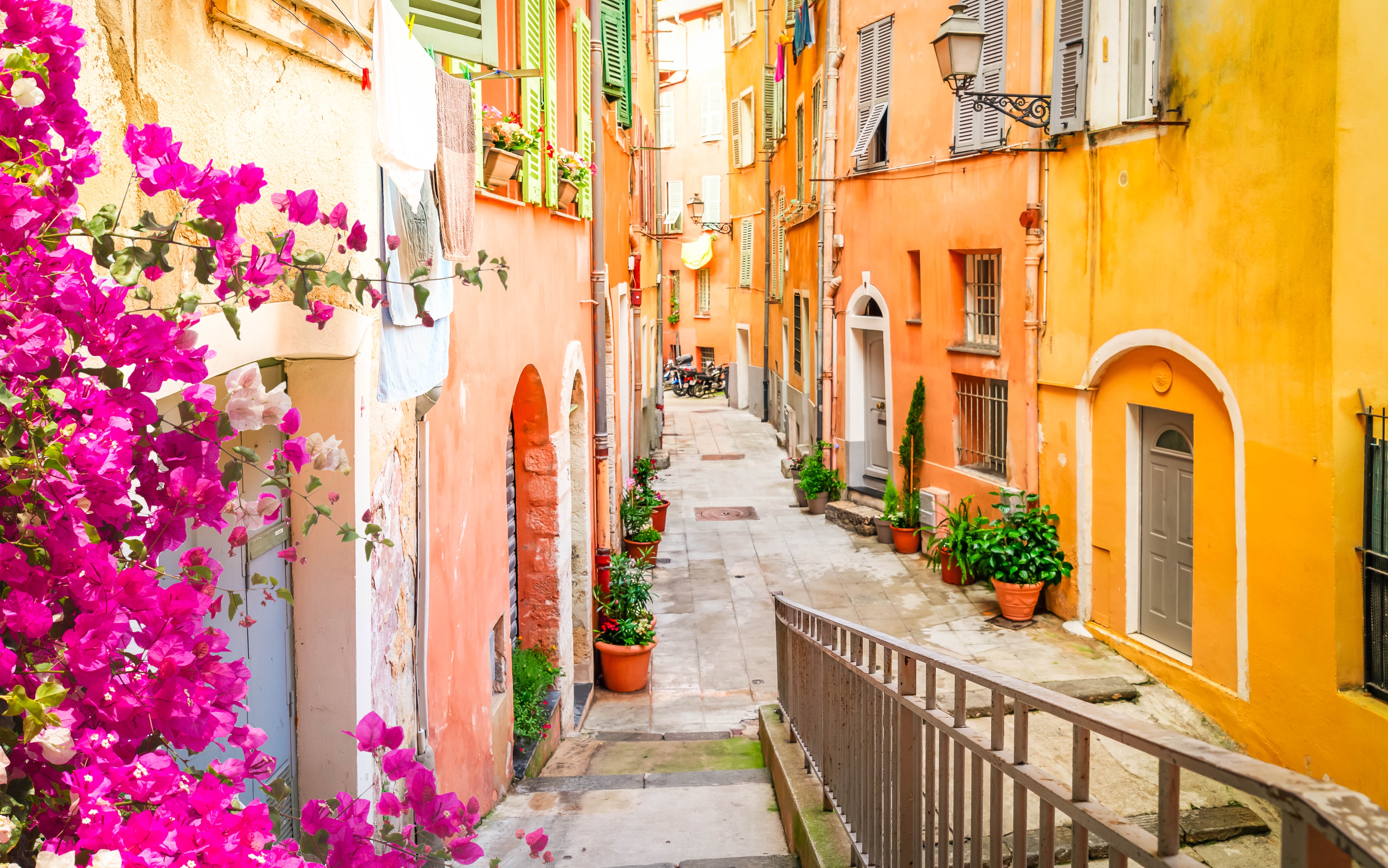 Farverige mediterrane gader med pink blomster og traditionel fransk arkitektur på den Franske Riviera