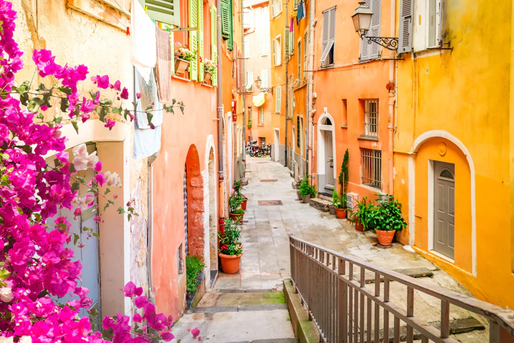 Farverige mediterrane gader med pink blomster og traditionel fransk arkitektur på den Franske Riviera