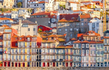 Farverige historiske bygninger langs Douro-flodens bred i Porto, Portugal med smukke refleksioner i morgenlyset
