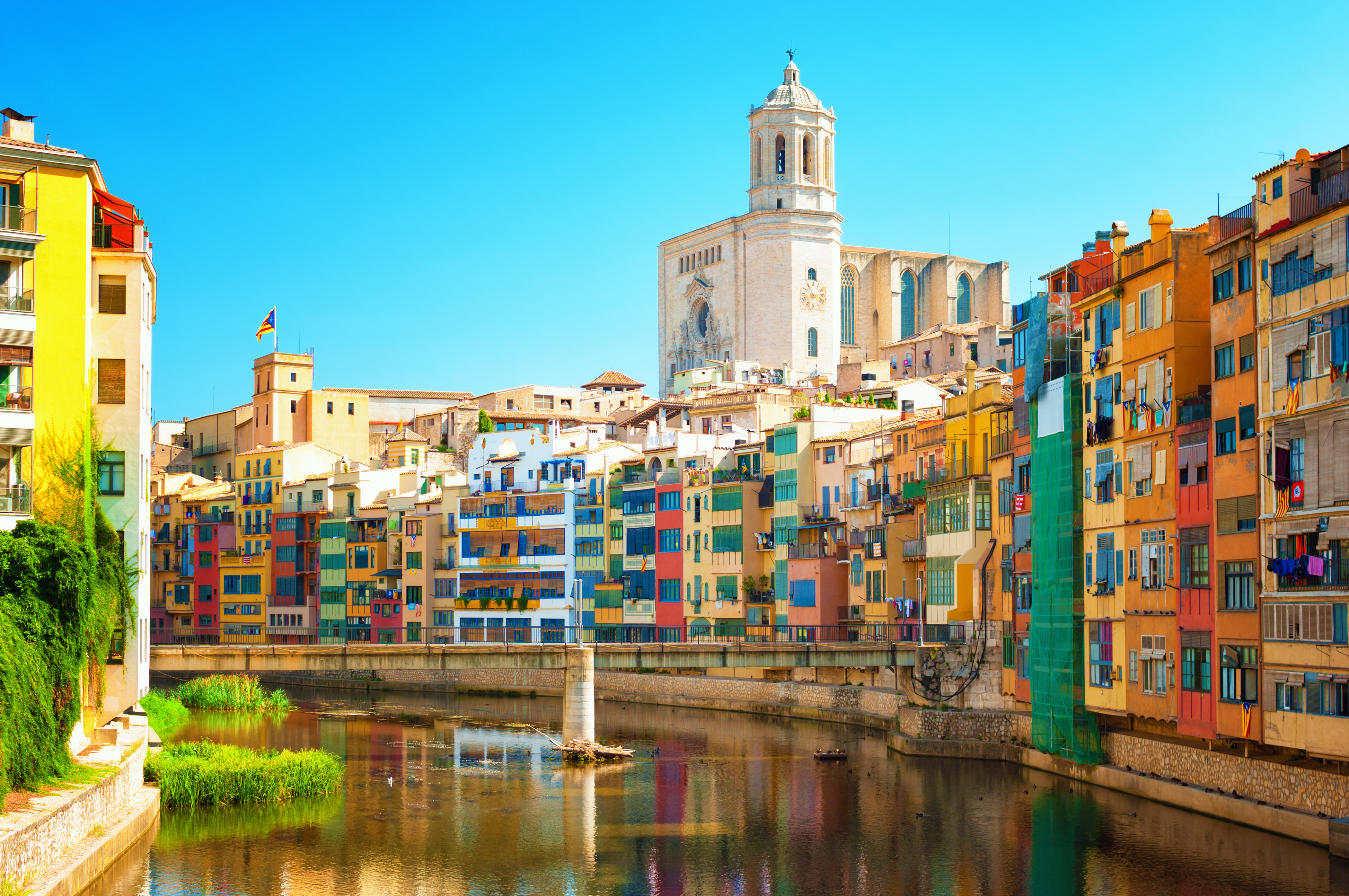 Farverige huse langs floden Onyar i Girona, Catalonien, Spanien, med Girona Katedral synlig i baggrunden