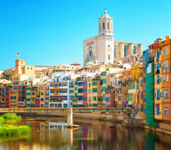 Farverige huse langs floden Onyar i Girona, Catalonien, Spanien, med Girona Katedral synlig i baggrunden