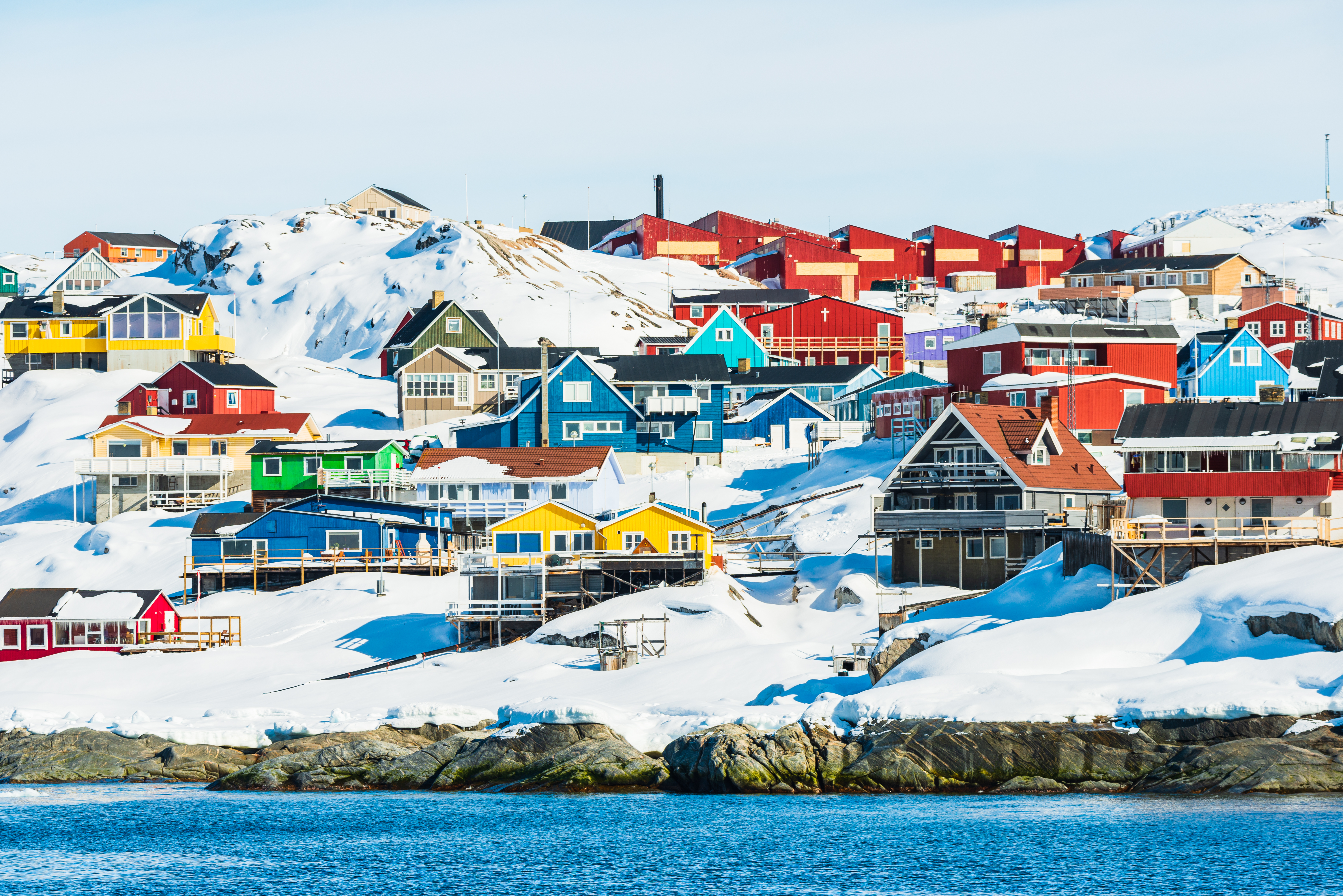 Farverige huse og bygninger i Ilulissat, Grønland, dækket af sne med udsigt over det arktiske vinterlandskab og havet