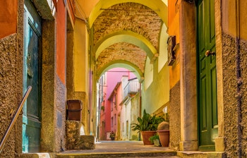 Farverige huse langs kysten i Riomaggiore, en charmerende landsby i Cinque Terre, Italien, med klart blåt vand og klippefyldt kyst