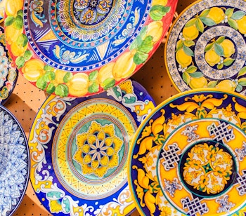 Traditionelle farverige keramik tallerkener fra Amalfi-kysten med håndmalede blå og gule mønstre, populære souvenirs fra Italien